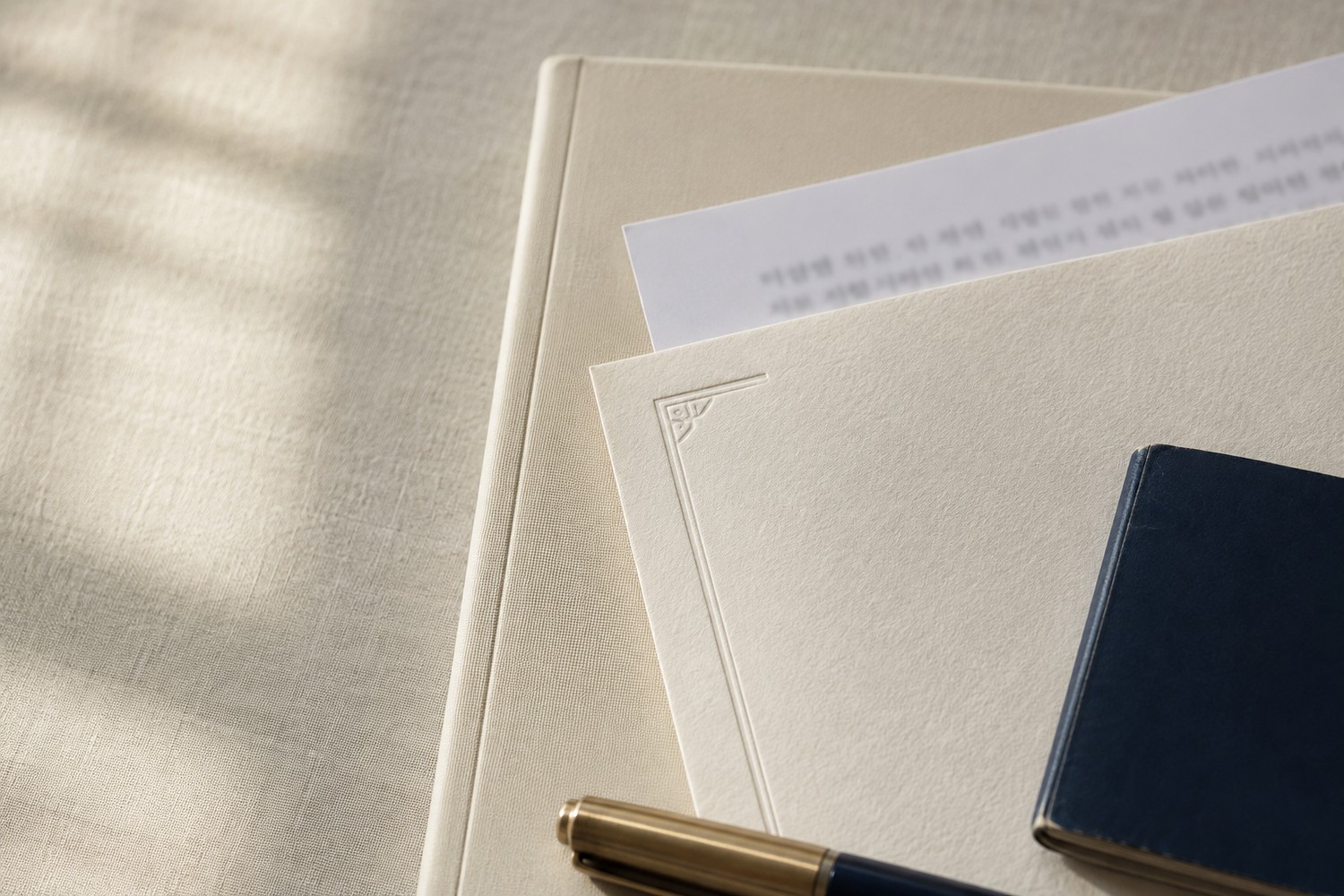 A foreign certificate and its Korean translation offset on a desk, with a navy travel document and a fountain pen
